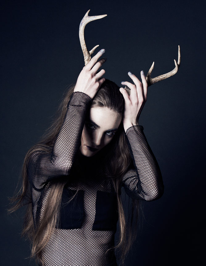 Dramatic portrait of girl holding deer antlers on her head