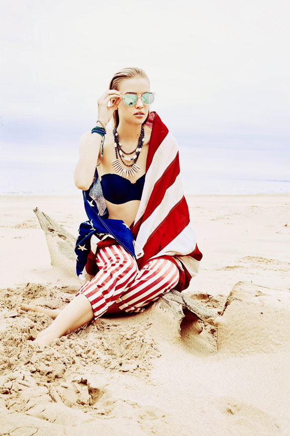 Girl wrapped in American Flag on beach