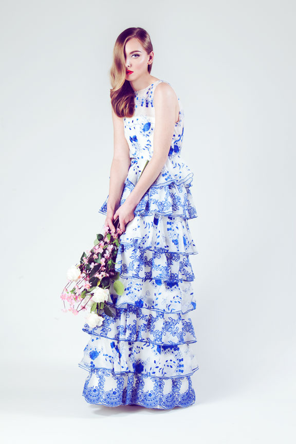 Model holding flowers in floral print ruffle dress